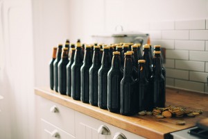 row of empty beer bottles and pile of caps on wood counter